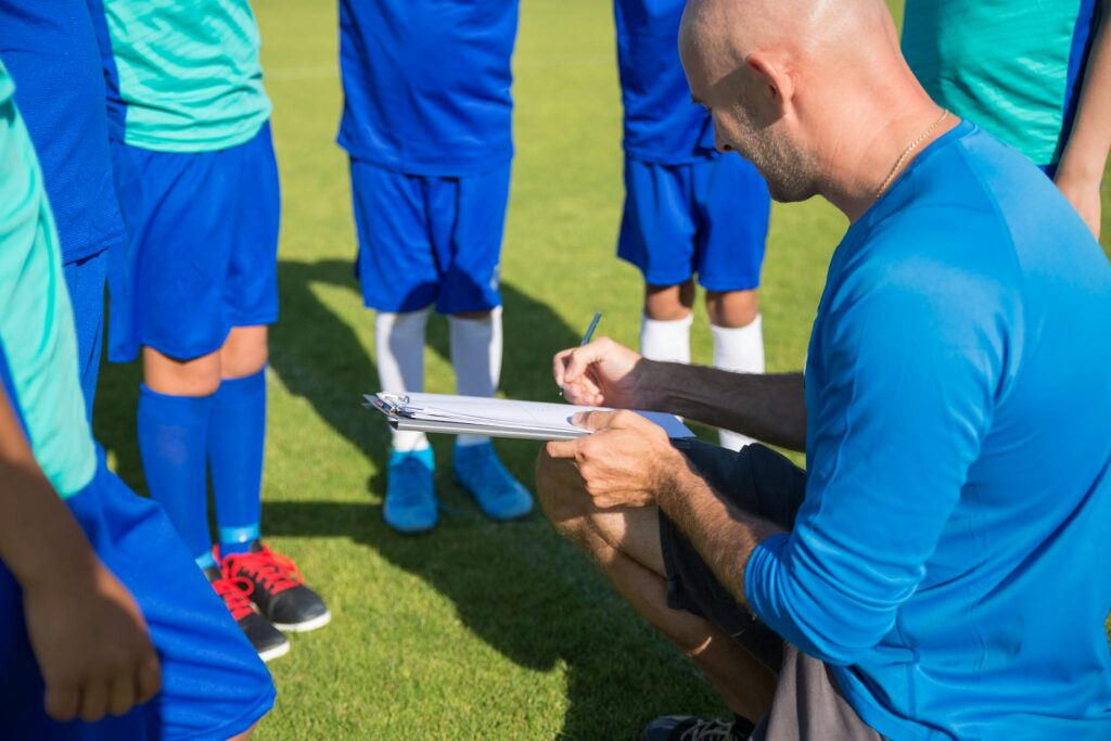 Soccer coach planning strategy with young players on sunny field