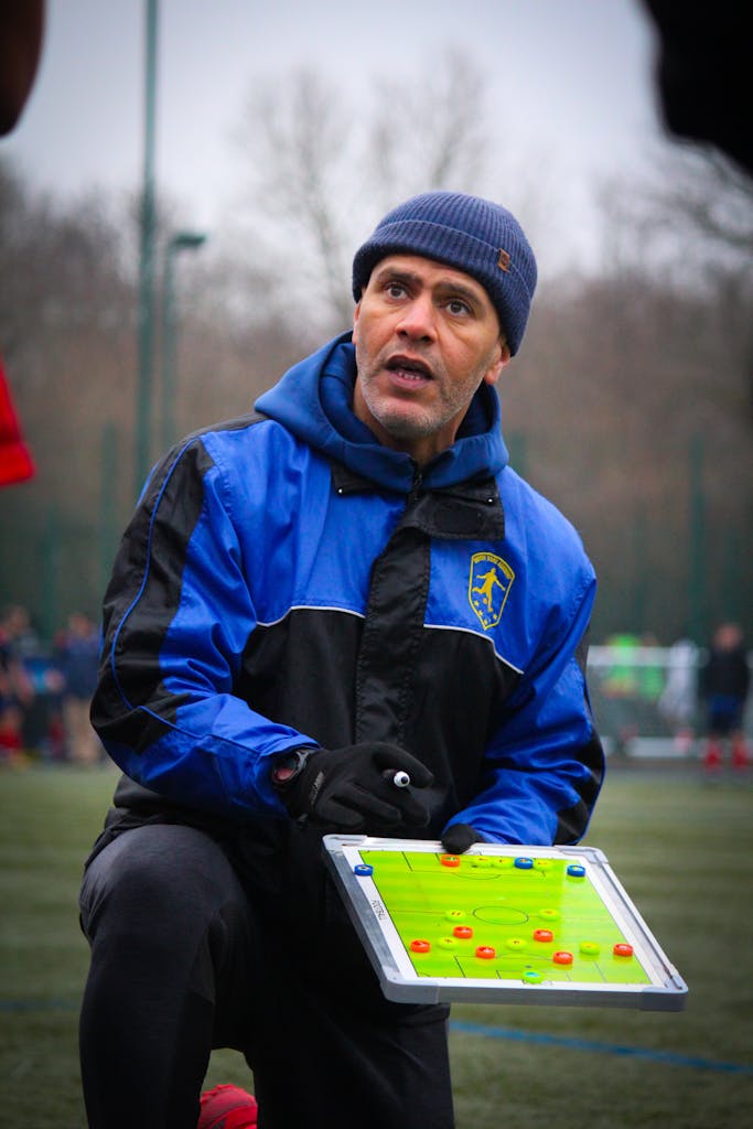 Soccer coach explaining strategy on field during training session.